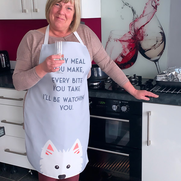 A lady in the kitchen wearing a personalised apron featuring her dog